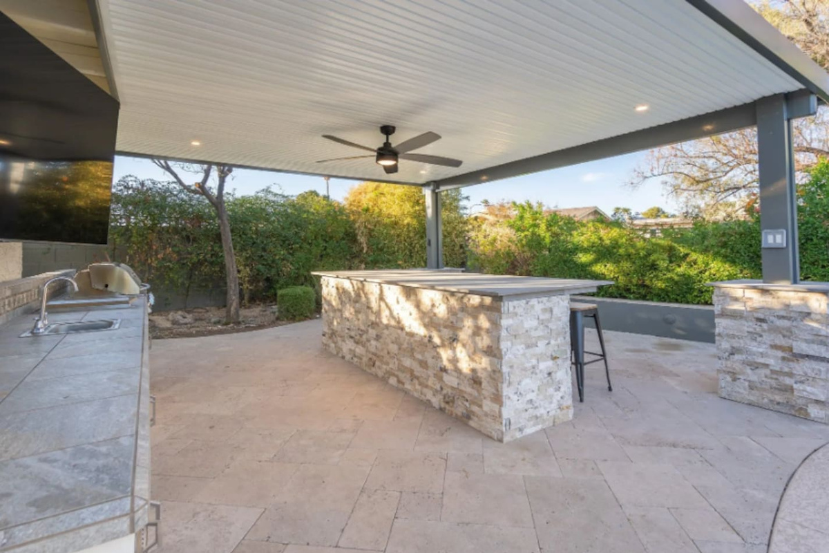 A stone-clad bar counter offers plenty of space to gather outdoors, shaded and ready for entertaining.
