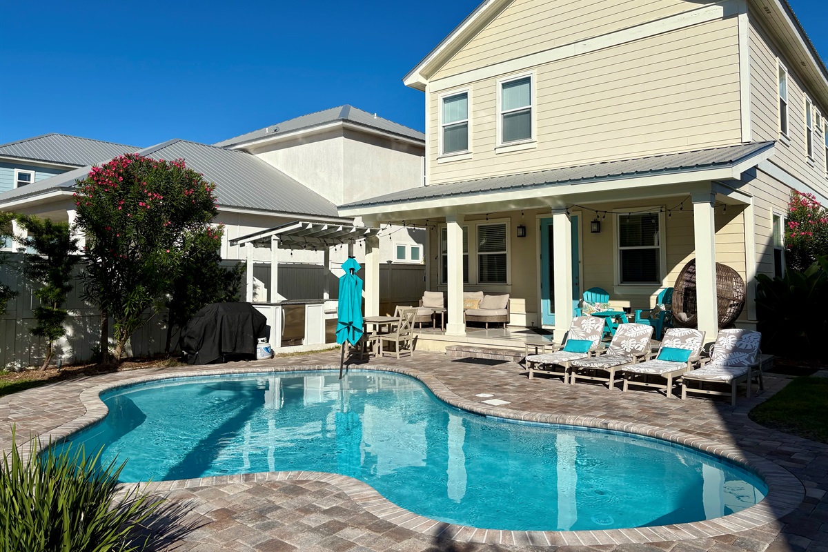 Resort-style backyard with heated private pool, covered patio, and lounge seating.