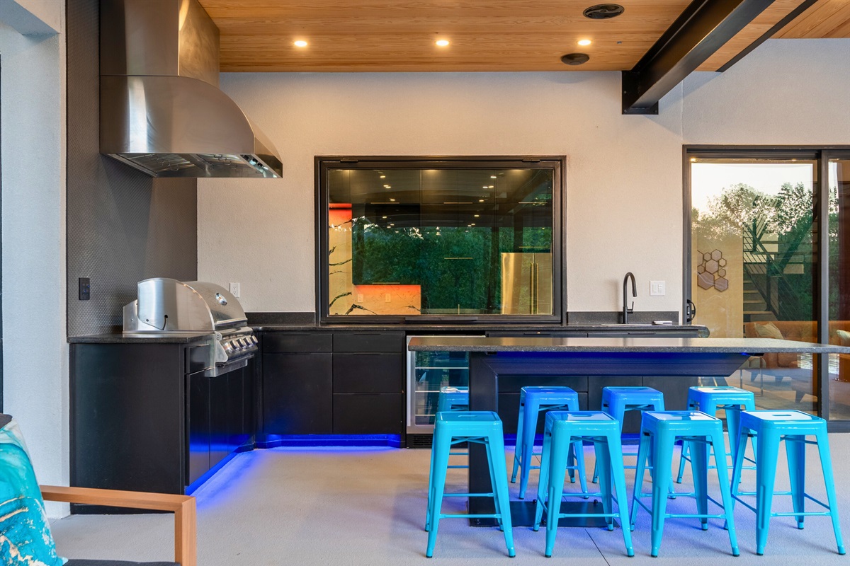 This stylish outdoor kitchen and bar area is perfect for hosting gatherings and enjoying al fresco dining.