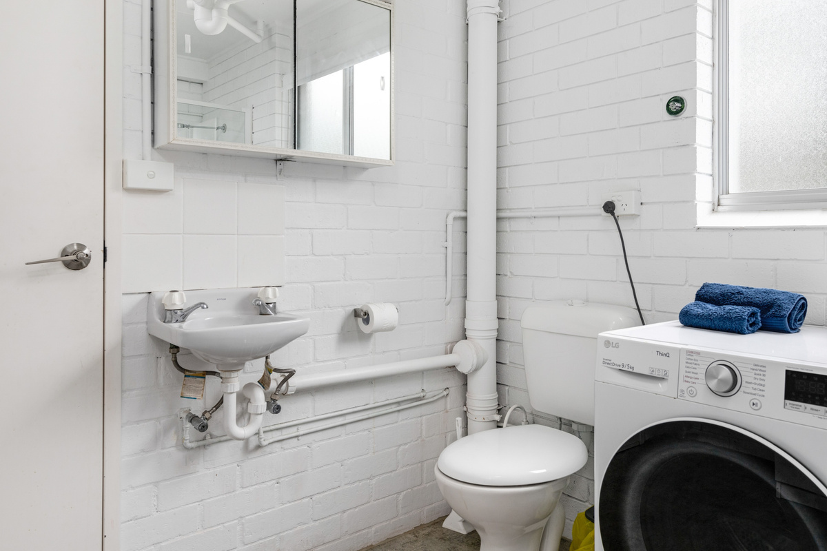 This downstairs bathroom and laundry combines a shower, toilet and washing space for the lower level of Skye’s Beach House.