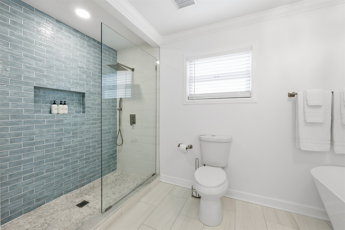 Walk-in glass shower with upscale tilework and a resort feel