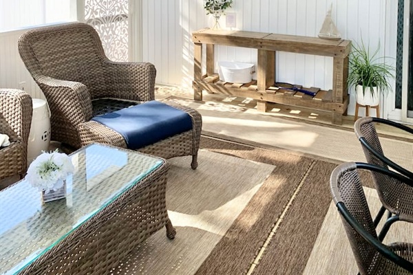 Experience the best of indoor-outdoor living in our screened-in sunroom. Kick back on navy wicker seating to watch the game or enjoy a meal at the large dining table—all while staying protected from the elements in a bright, coastal setting.