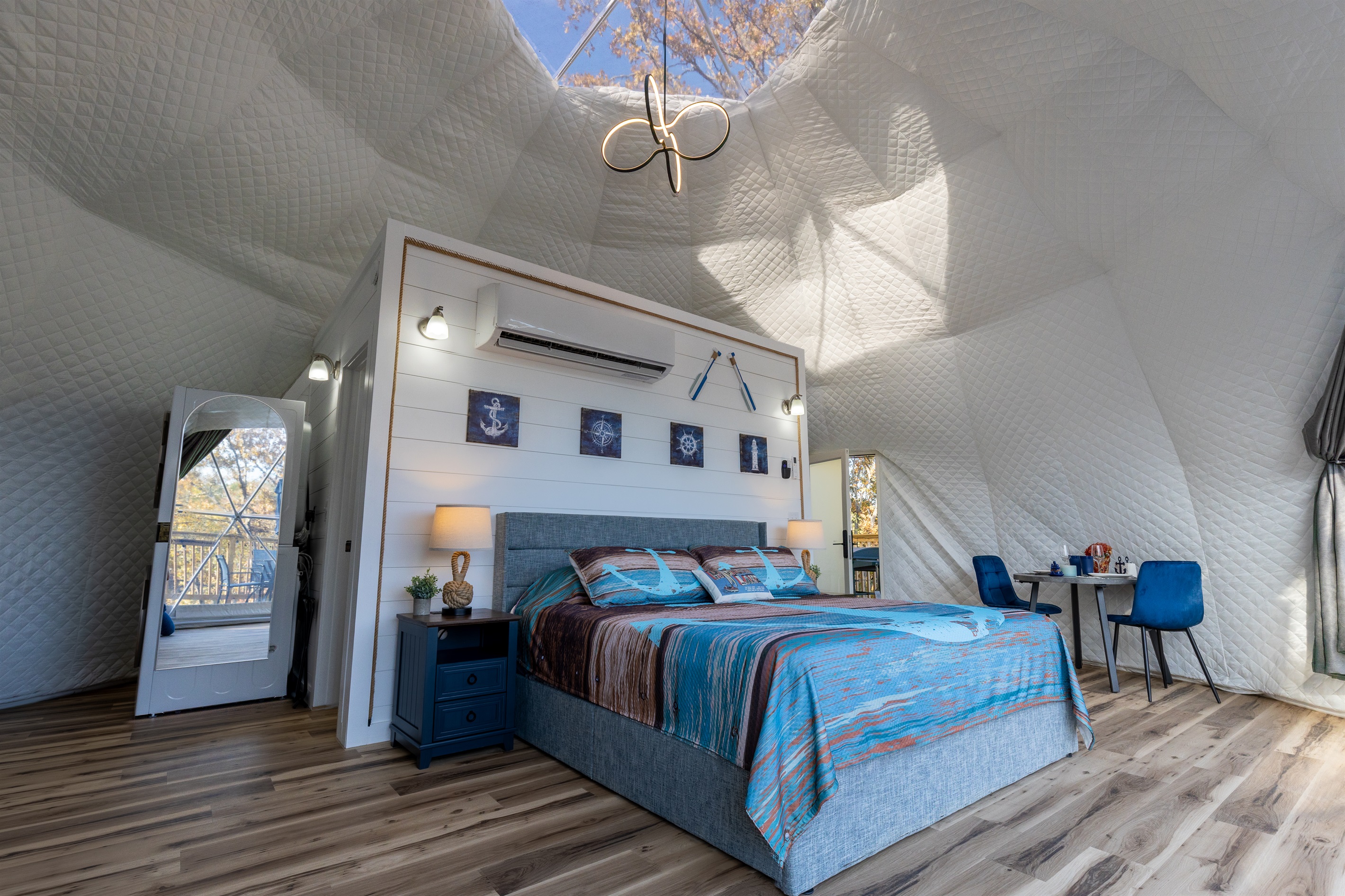 Spacious open-concept layout with a king bed, vaulted dome ceiling, modern lighting, and stunning views through the panoramic window wall