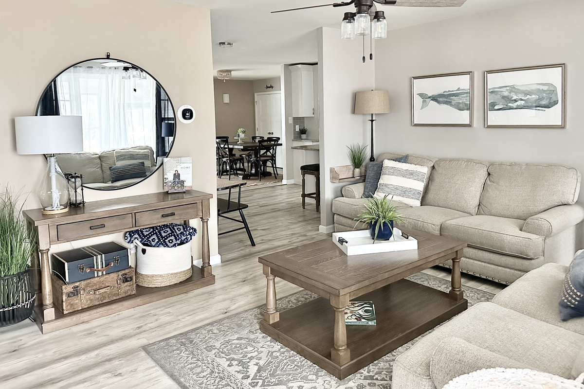 Relax in our modern farmhouse living room featuring a plush sectional, rustic wood accents, and coastal decor. This open-concept space flows into the dining area, perfect for movie nights or morning coffee in a bright, airy atmosphere.