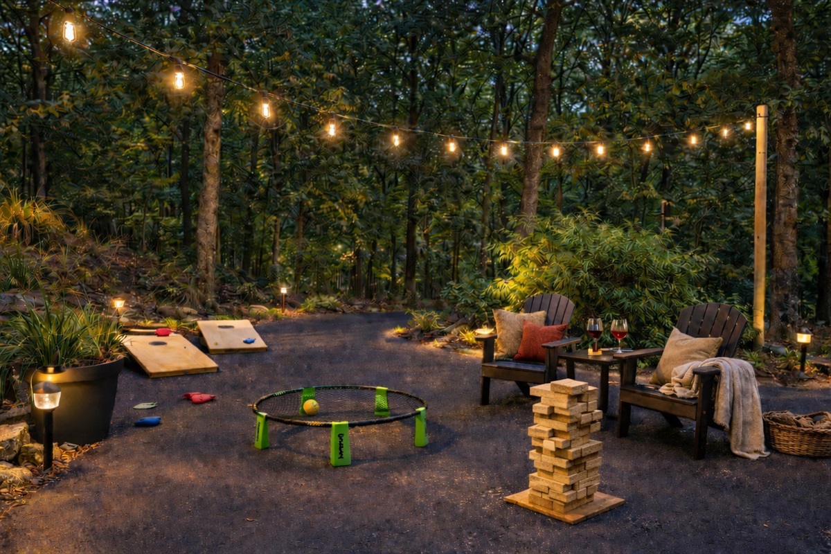 Cornhole, spikeball, giant Jenga, and lounge chairs all set up and ready — the yard games area is lit at dusk and stays busy all day before that.
