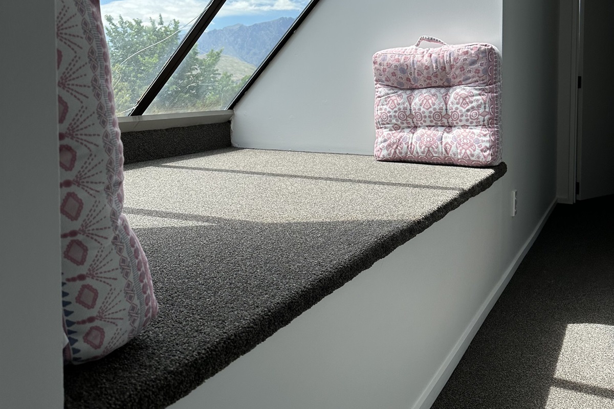 Fernhill Mountain Escape’s upstairs sunbed catches alpine light through the oversized window, with a quiet spot to take in views toward The Remarkables.