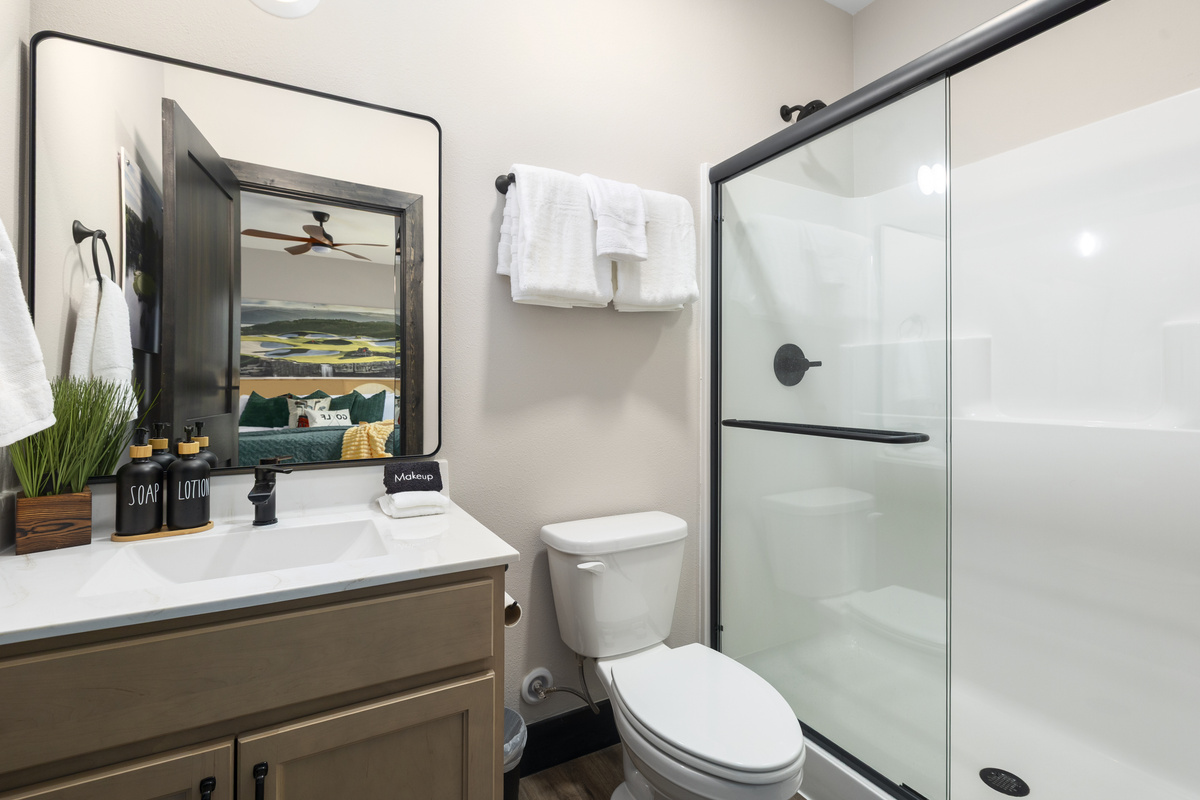 Lit mirror, wood vanity, and a spacious walk-in shower.
