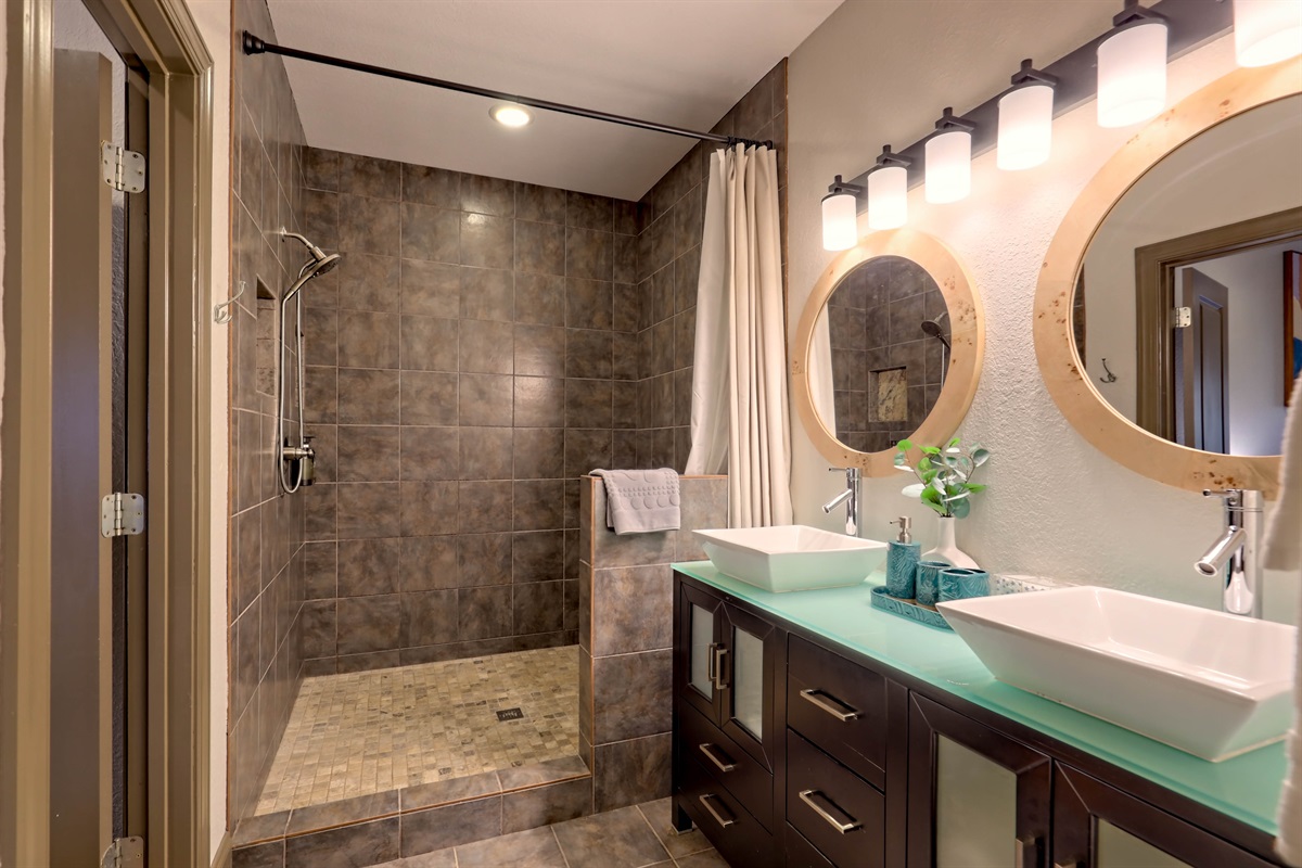 Large tiled walk-in shower with double vanities.