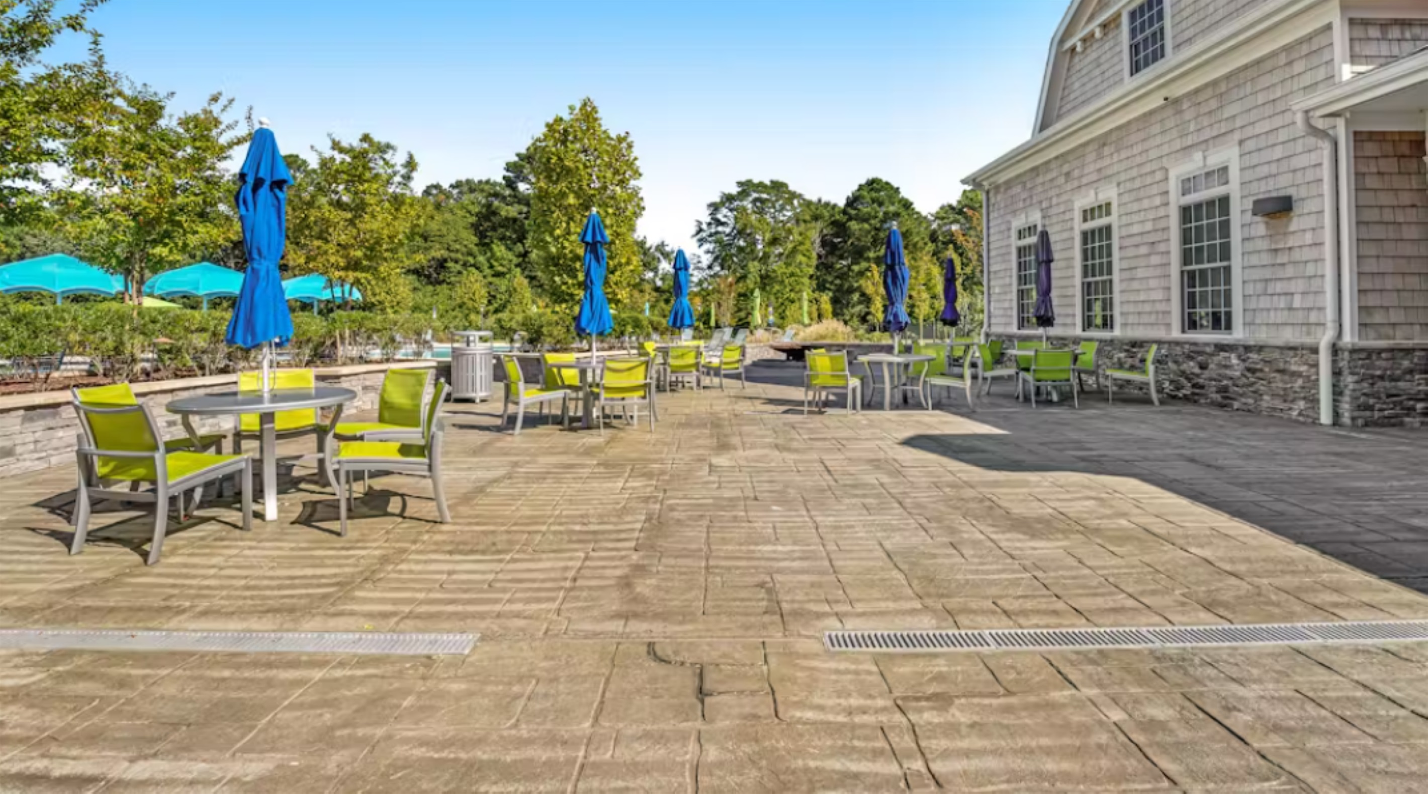 Clubhouse outdoor patio featuring umbrella-shaded tables and seating—ideal for al fresco dining, socializing, or poolside relaxation.