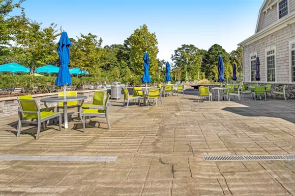 Clubhouse outdoor patio featuring umbrella-shaded tables and seating—ideal for al fresco dining, socializing, or poolside relaxation.