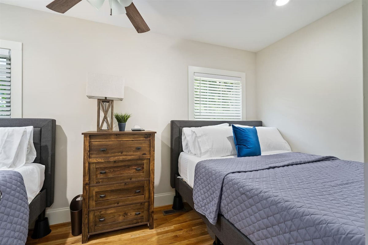 A tranquil retreat featuring two queen beds, warm wood furnishings, and soft, inviting bedding.
