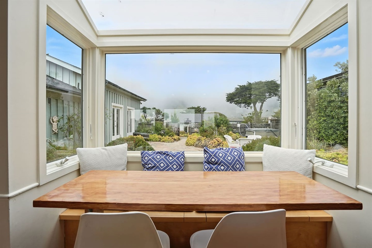 - Dining nook with panoramic windows overlooking the garden courtyard  
- Wooden table paired with modern chairs and cozy bench cushions  
- Inviting spot for meals while enjoying views of the outdoors year round 