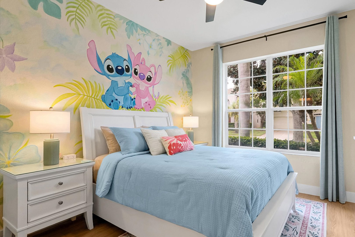 Stitch Queen Retreat: Queen-size bed framed by a colourful tropical mural, with closet storage and direct access to a private ensuite.
