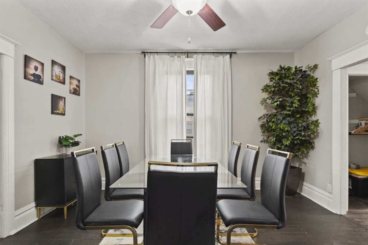 Elegant dining area featuring a sophisticated table with matching chairs, stylish decorations, plush curtains, and a chandelier ceiling fan—creating a refined and inviting atmosphere perfect for entertaining and dining in style