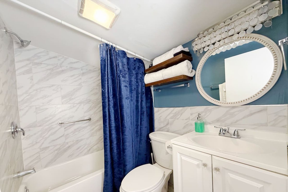 This en suite bathroom, accessible from the primary queen bedroom, is clean and modern with marble tile, plush towels, and a full bathtub. Perfect for relaxing after a long day exploring the French Quarter and Marigny. 