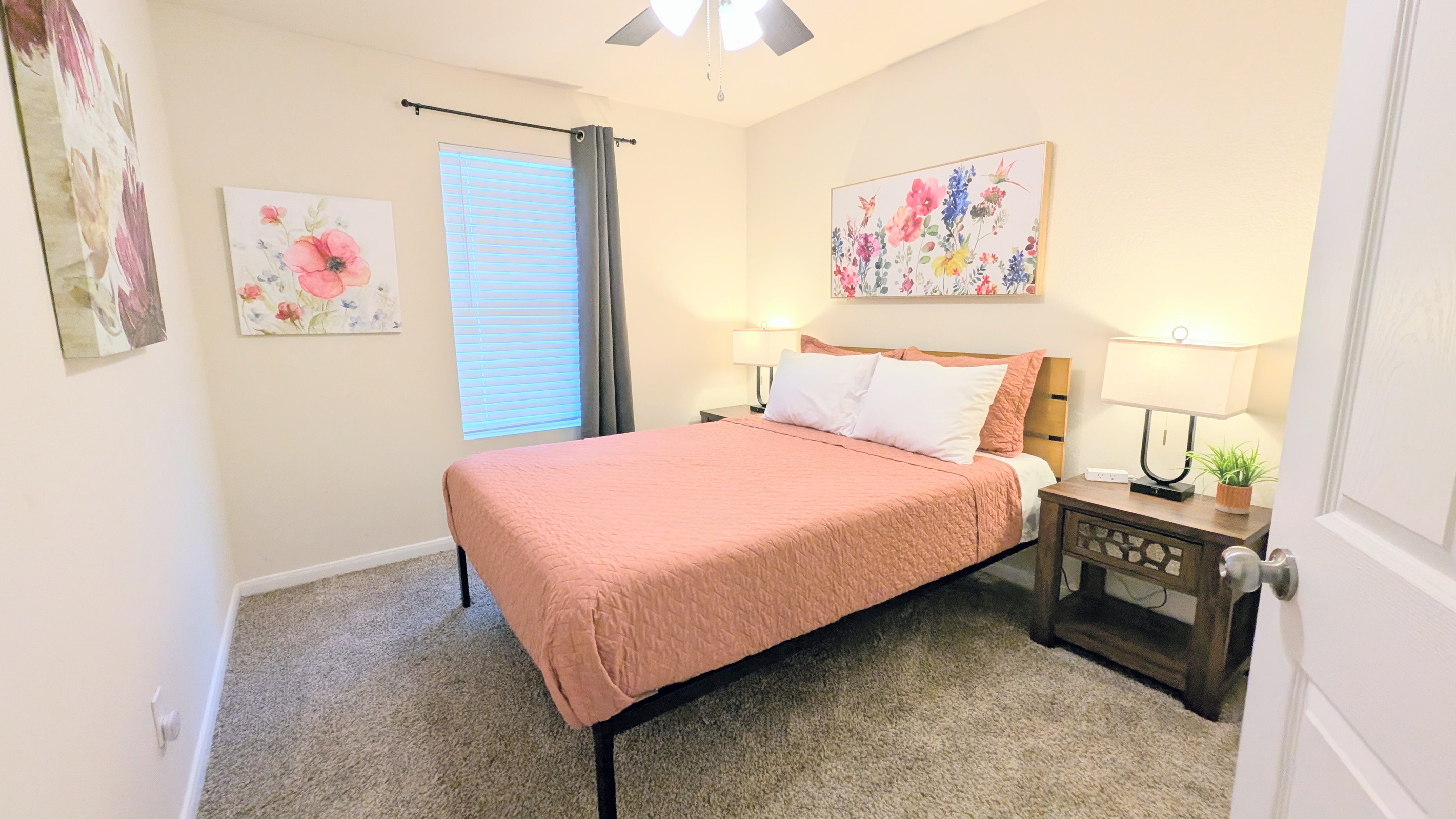 This bedroom features a comfortable queen bed with sheets, blanket, quilt and plush pillows. Convenient charging ports, room darkening curtains and blinds, alarm clock, and ceiling fan are provided. 