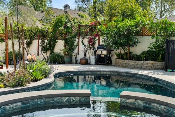 The tranquil beauty of the backyard, blending the soft glow of the houses with the shimmering pool.