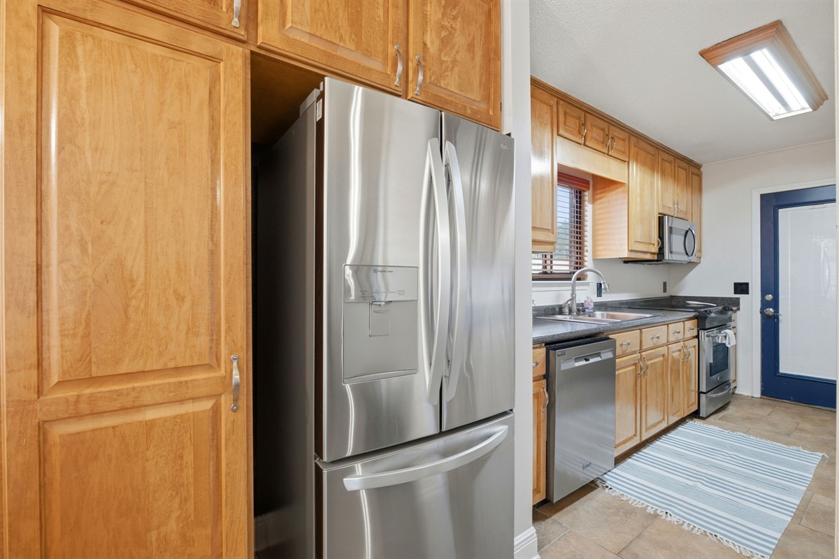 A modern stainless steel refrigerator and dishwasher complement the kitchen’s clean and functional design. With plenty of cabinet space and an efficient layout, this kitchen is ideal for everyday cooking and organization.