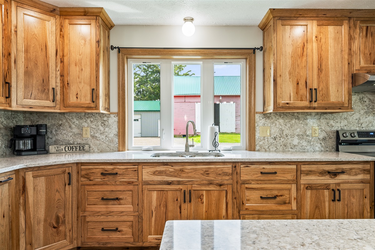 This beautiful kitchen boasts expansive counter space, rich wood cabinets, modern lighting, and scenic views, perfect for any cooking enthusiast.