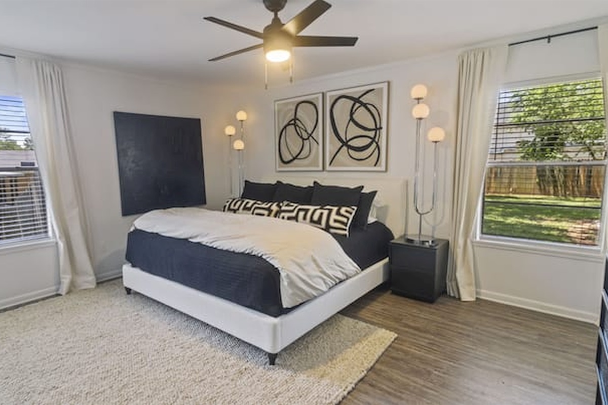 Comfortable king bedroom with large windows and soft natural light.