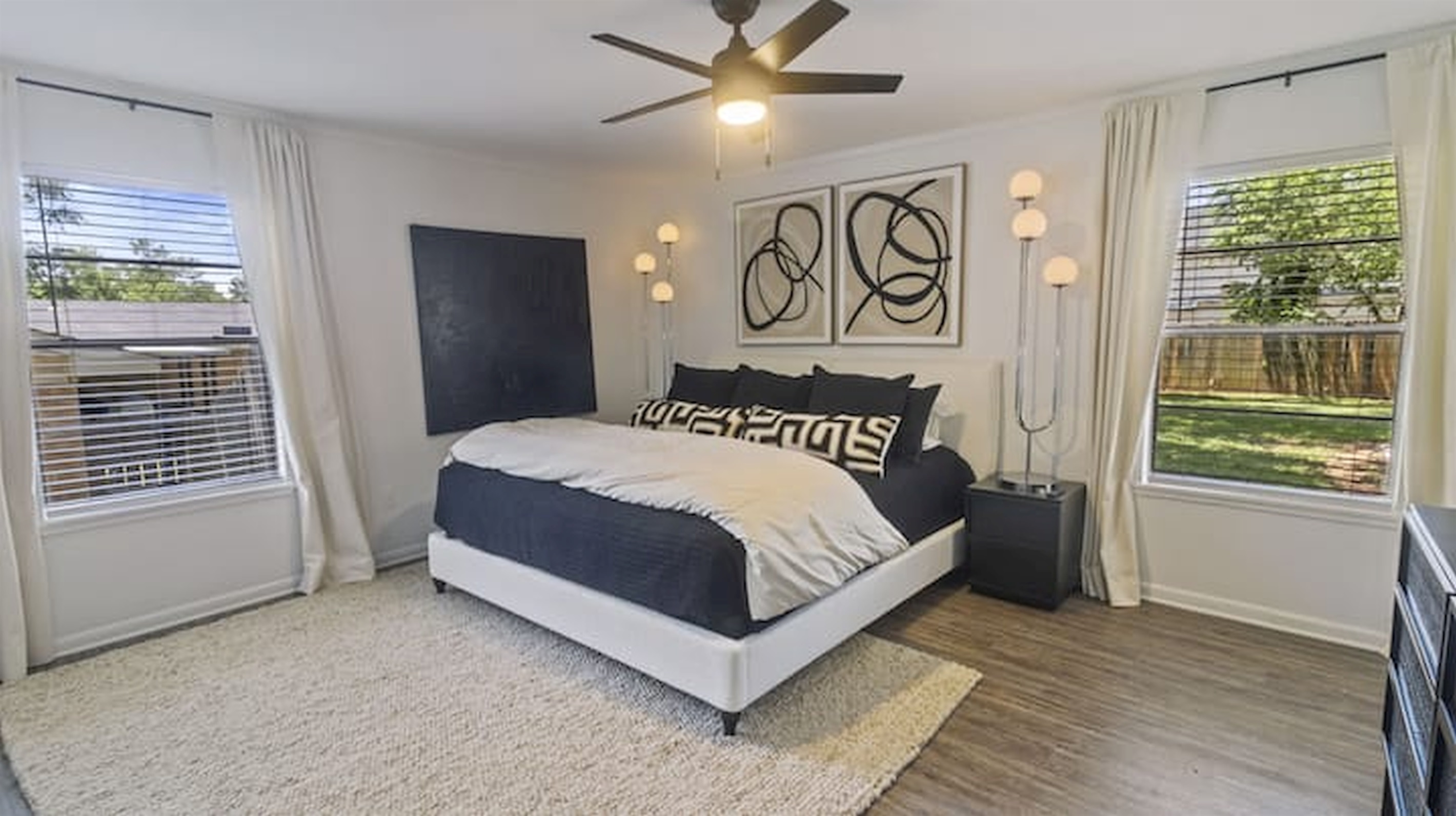 Comfortable king bedroom with large windows and soft natural light.