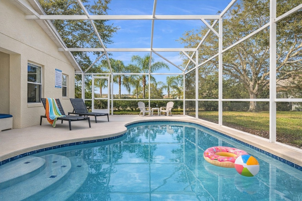 Relax by the screened-in pool with lounge chairs and outdoor seating in a serene setting.