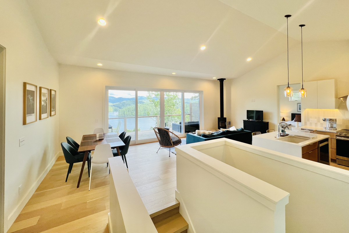 Gather with a view. The open-concept main level combines the kitchen, dining area, and living room into one inviting space. Large sliding glass doors open to the covered deck, where sweeping views of Lake Santeetlah and the mountains take center stage.