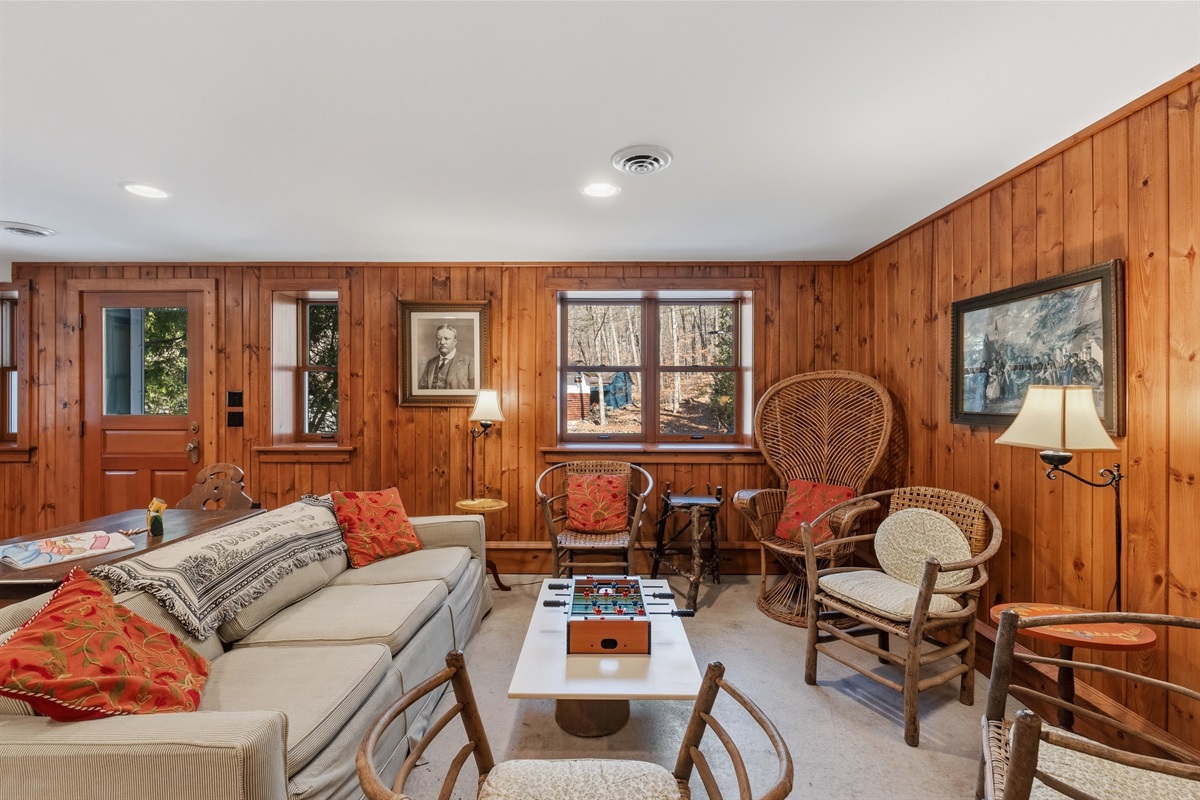 Walkout lower level sitting area w/ cozy seating & warm wood-paneled walls