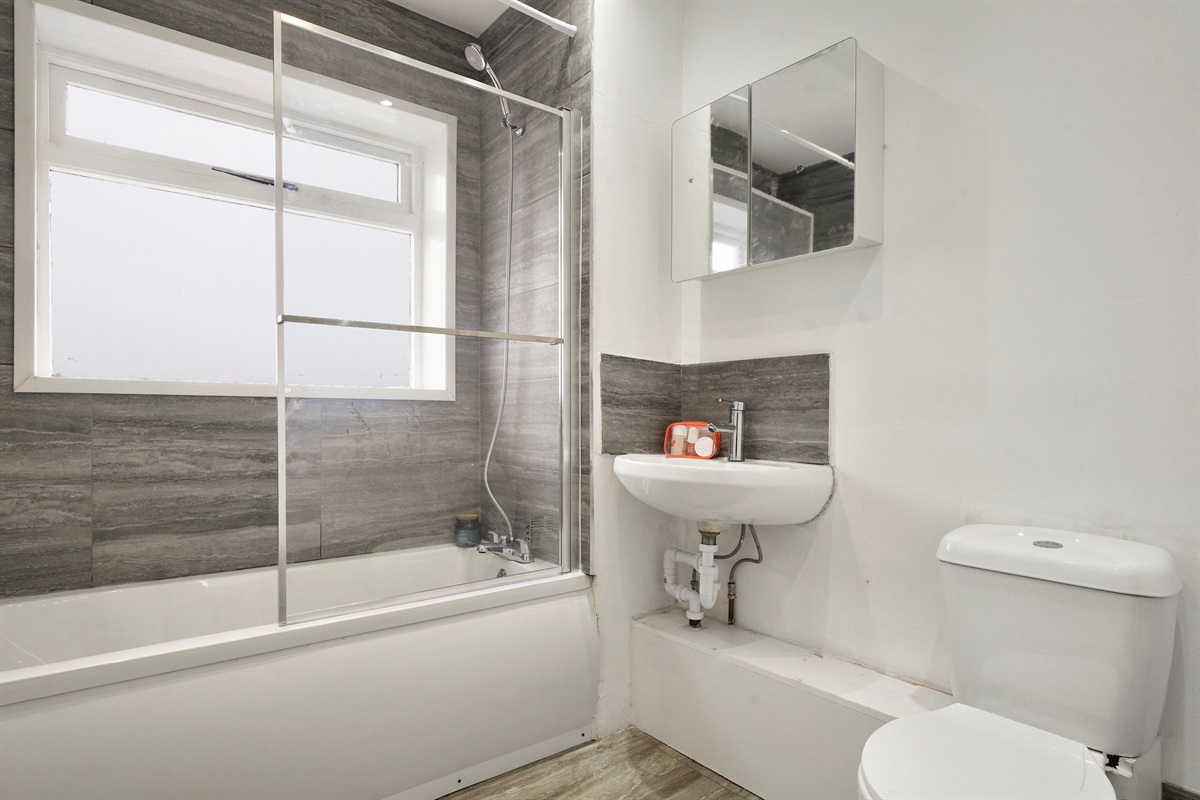 [shower-over-bath, mirrored storage, bright ventilation window]