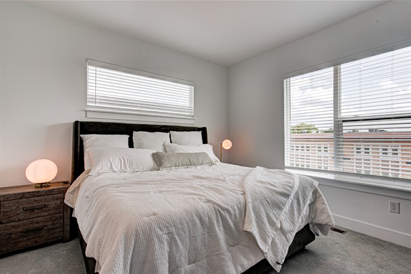 Relax in the serene master bedroom featuring a comfortable king-size bed, soft linens, and cozy pillows. Includes nightstands, lamps, walk-in closet, and full-length mirror for added comfort.