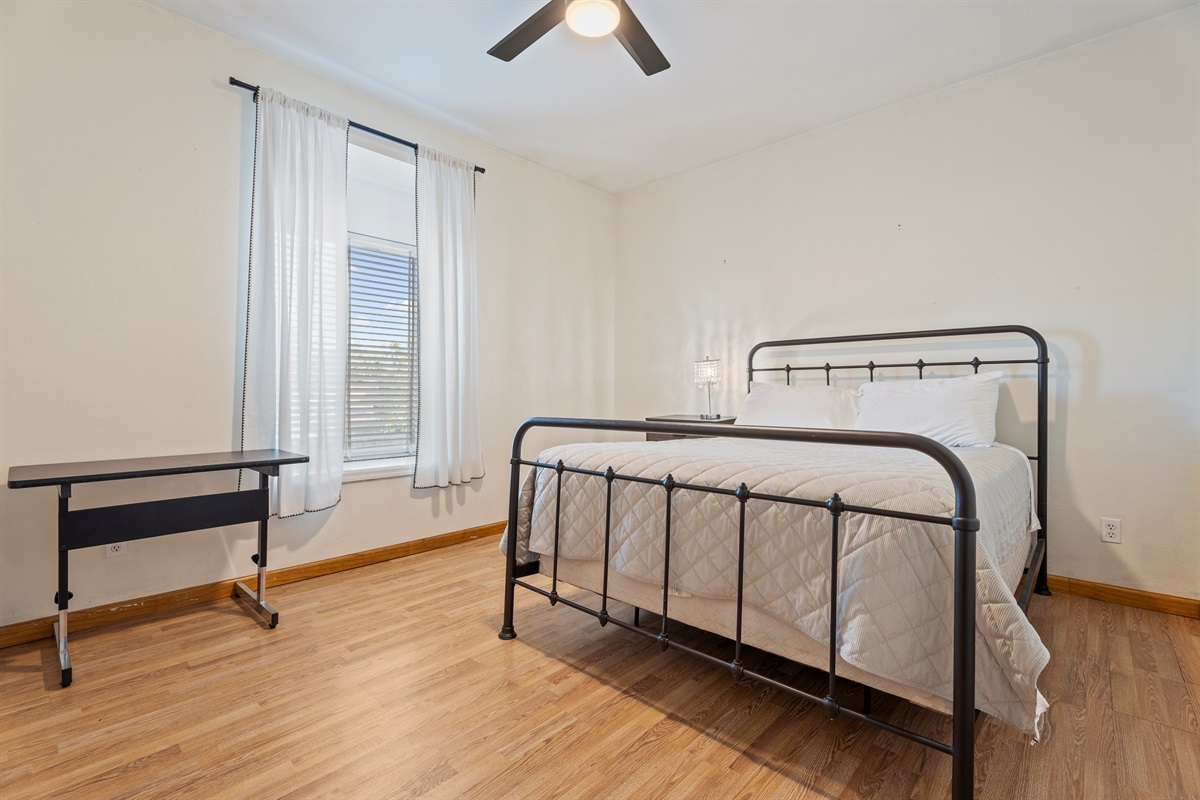 This sun-drenched bedroom blends modern simplicity with cozy charm, offering a metal-frame bed and a restful ambiance.