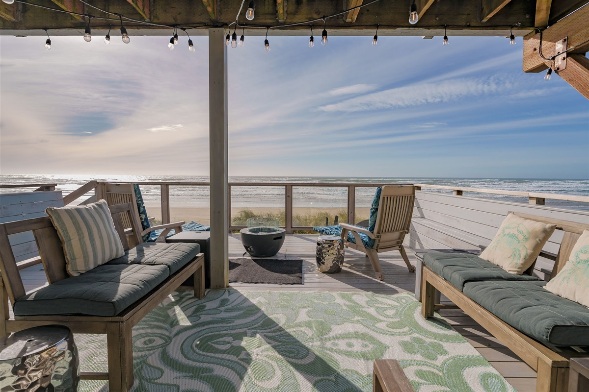 The deck is adorned with an array of comfortable outdoor furniture, including a propane bbq grill and string lights that invite relaxation