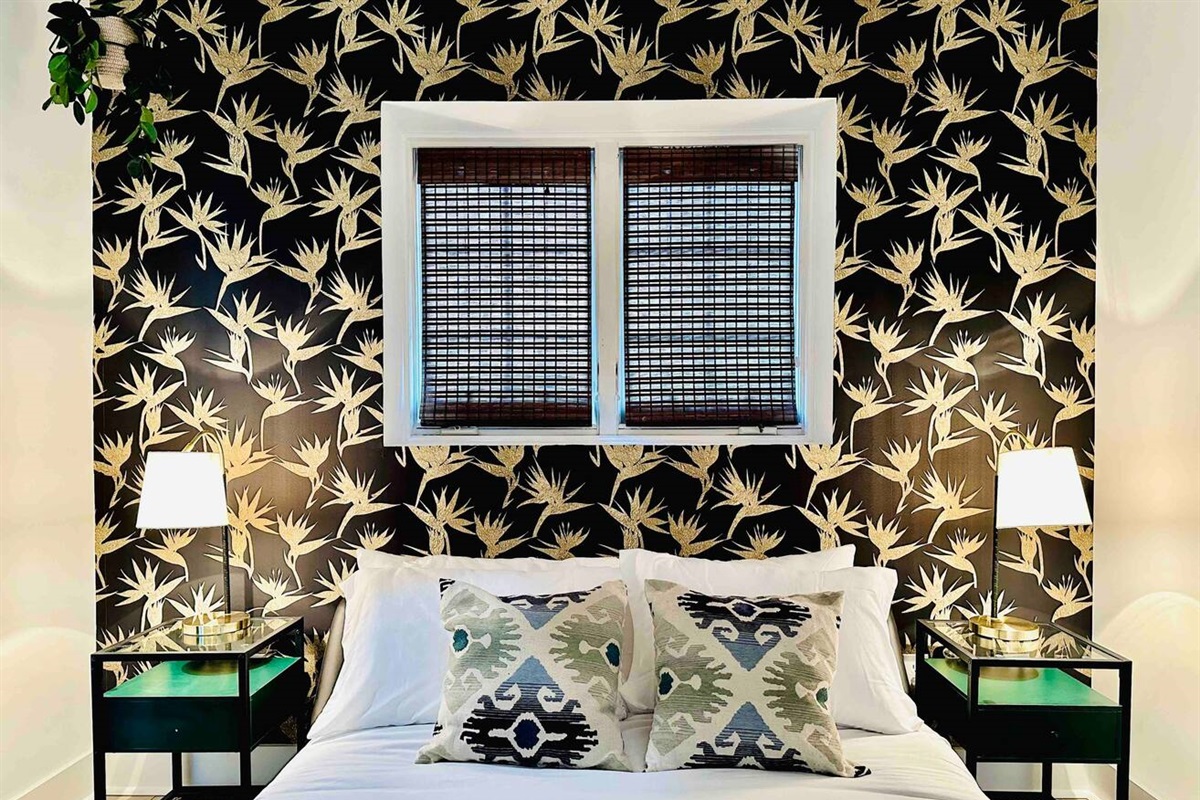 Fun tropical wallpaper decorates the bedroom with two nightstands and reading lamps!