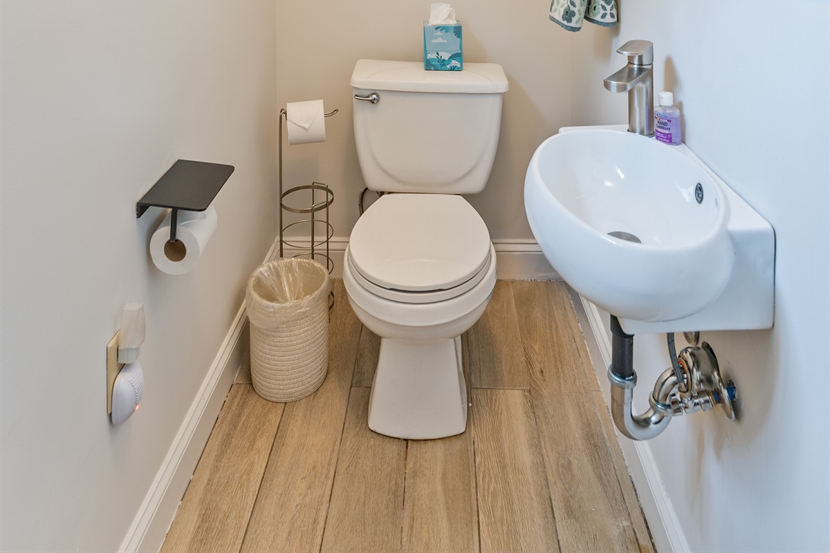 Bright and stylish half bath featuring nautical artwork, wood-style floors, and a sleek modern sink—perfect for guest convenience! Just off the living room on the main floor