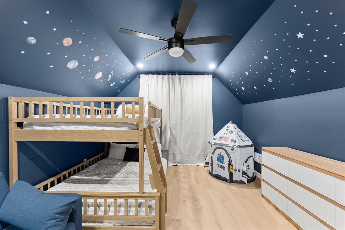 Glow-in-the-dark stars on the ceiling add a magical touch to this space-themed room.