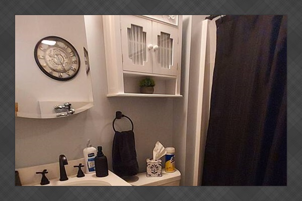 Designed for refined taste, this men’s bathroom features a sleek wall-mounted urinal, a mirrored Kohler medicine cabinet, and over-the-toilet storage. Black accents add bold contrast and modern polish to this calm, carefully curated space.