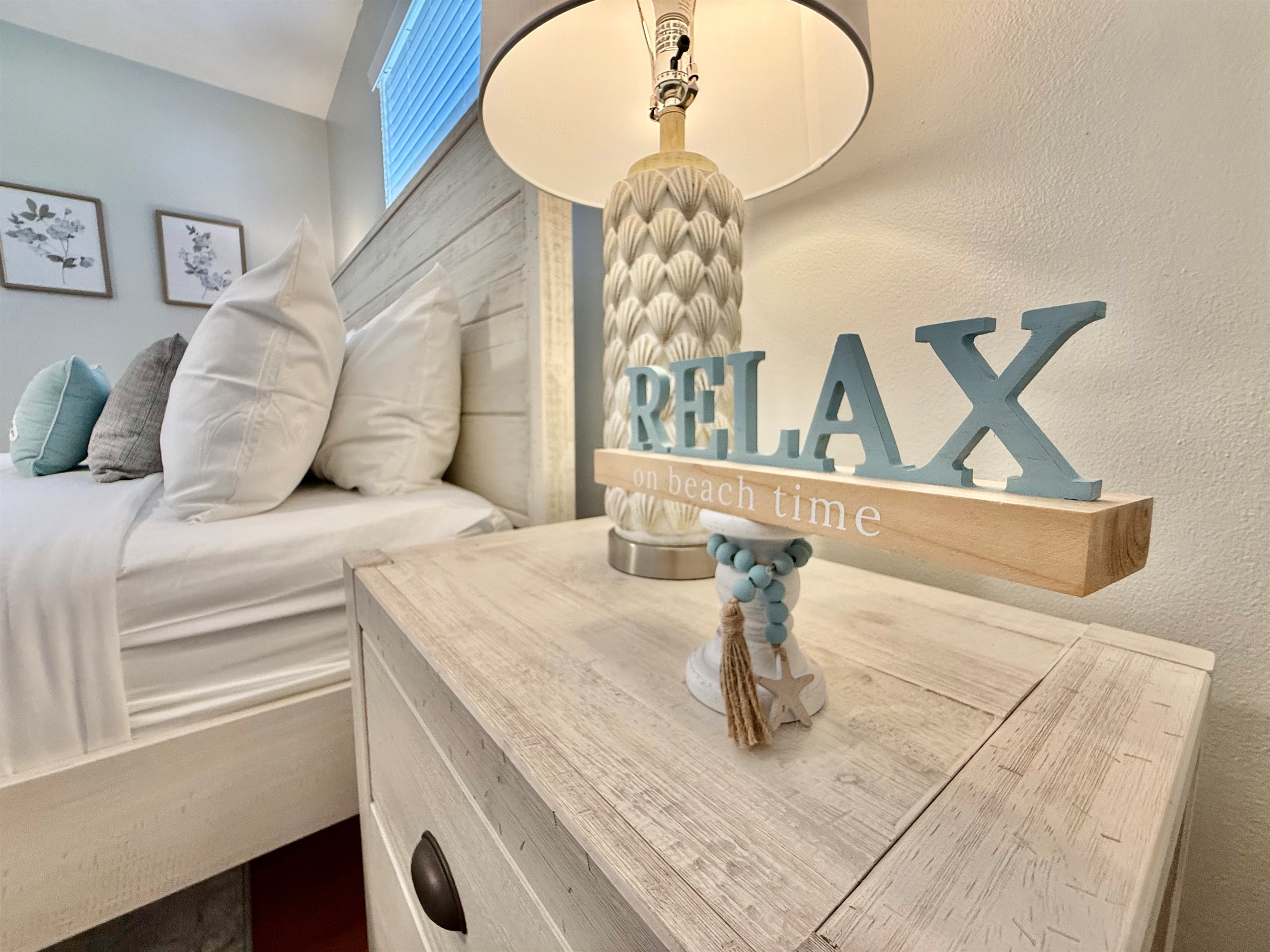 A tranquil haven featuring a stylish wood bed frame, fresh linens, and calming sea-inspired decor.