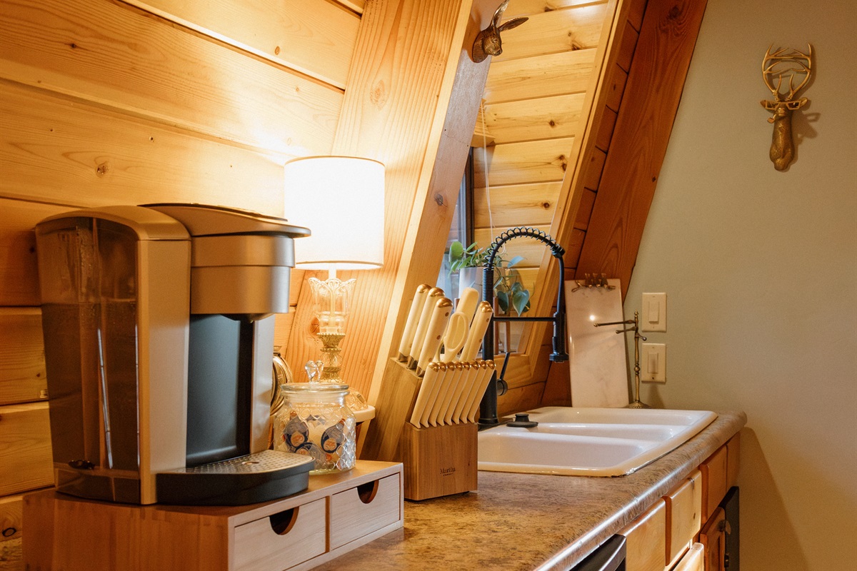 The compact kitchen at Poppywood Pines features granite countertops, Keurig coffee maker, and farmhouse sink beneath dramatic A-frame beams. This efficient Show Low cabin provides everything needed for your White Mountains vacation cooking and entertaining