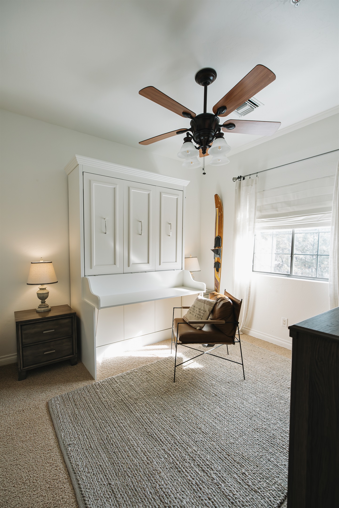 Calm, light-filled bedroom with ceiling fan, ample storage, and cozy reading chair—perfect for unpacking, working remotely, or enjoying a peaceful mountain getaway.