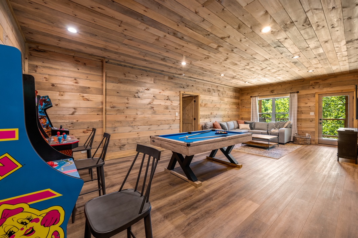 Game room with three arcade games, a pool table, and a large screen TV.