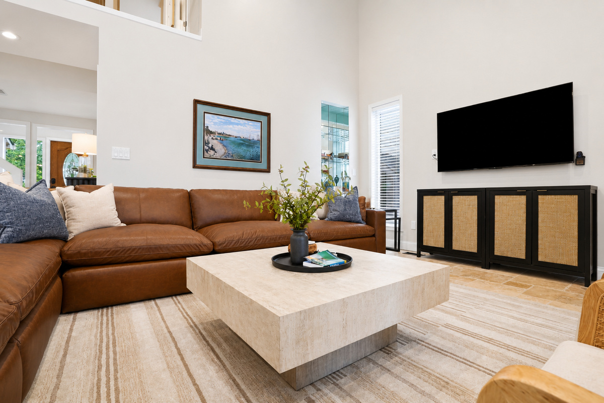 Cozy living room with a large sectional, modern TV console, and clean minimalist design. Bright, comfortable space perfect for relaxing and unwinding.