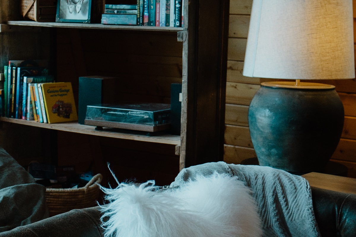 Curated mountain cabin details create a cozy reading nook with plush seating, warm wood walls, and soft textures. This A-frame retreat in Show Low is perfect for relaxing after hiking or enjoying a quiet White Mountains getaway.