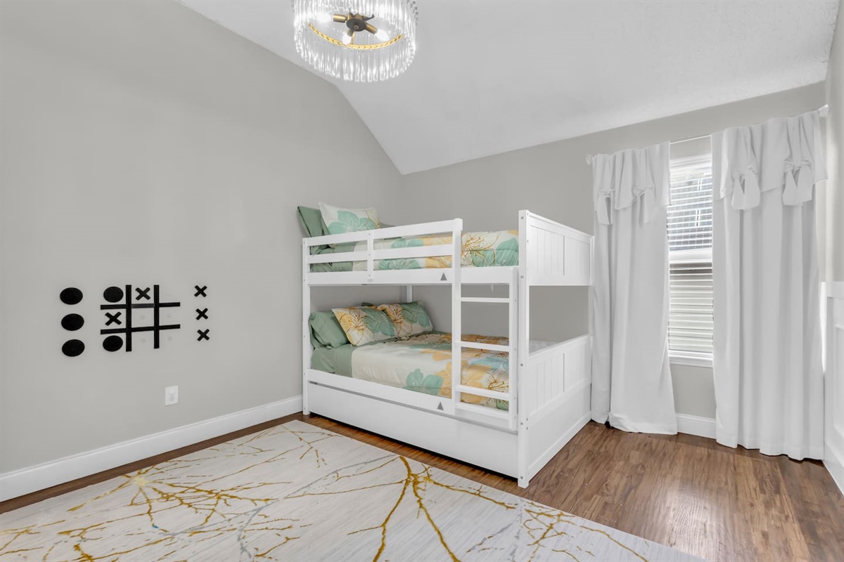 Spacious bunk bedroom featuring queen-over-queen bunk beds, room-darkening blinds, ceiling fan, fresh bed linens, and a comfortable layout for group stays.