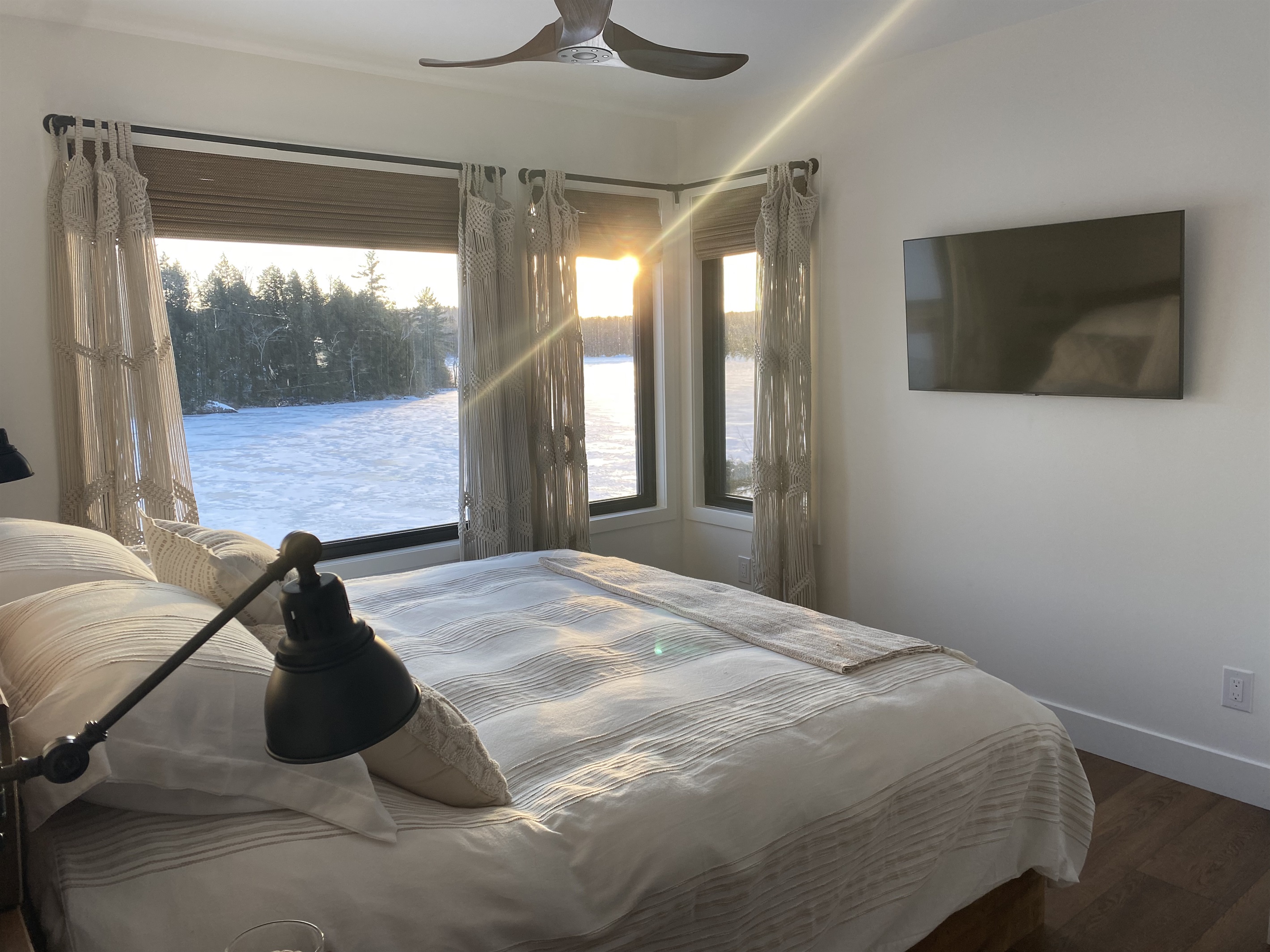 Bedroom 1 on main level with king bed, large smart TV and corner view of Lac McGregor