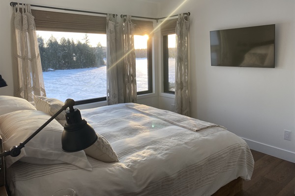 Bedroom 1 on main level with king bed, large smart TV and corner view of Lac McGregor