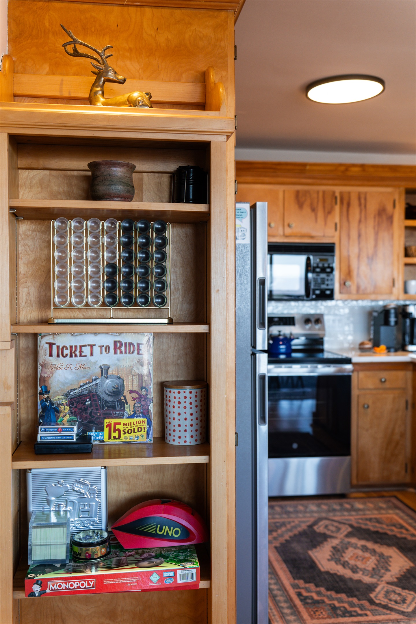 Find a selection of board and card games stored in the open shelf cabinet in the kitchen.