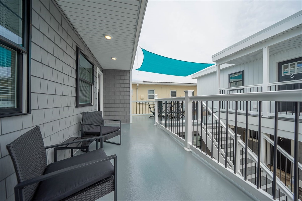 Shared outdoor walkway with seating, ideal for a quiet moment outside or morning coffee. Covered shade sail offers comfort throughout the day, with easy access to the unit and a relaxed coastal atmosphere.