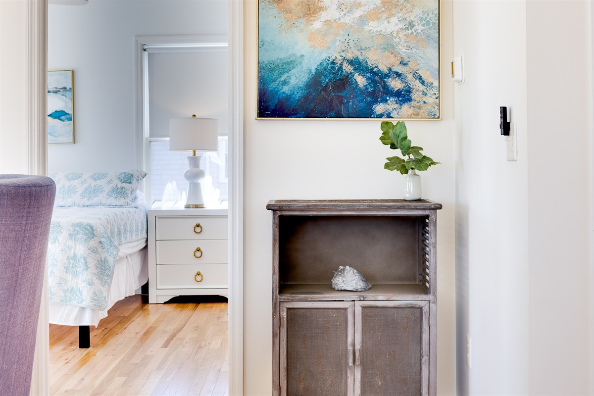 Entry to the upstairs master bedroom&mdash;coastal artwork, warm wood floors, and a calm transition into your private retreat