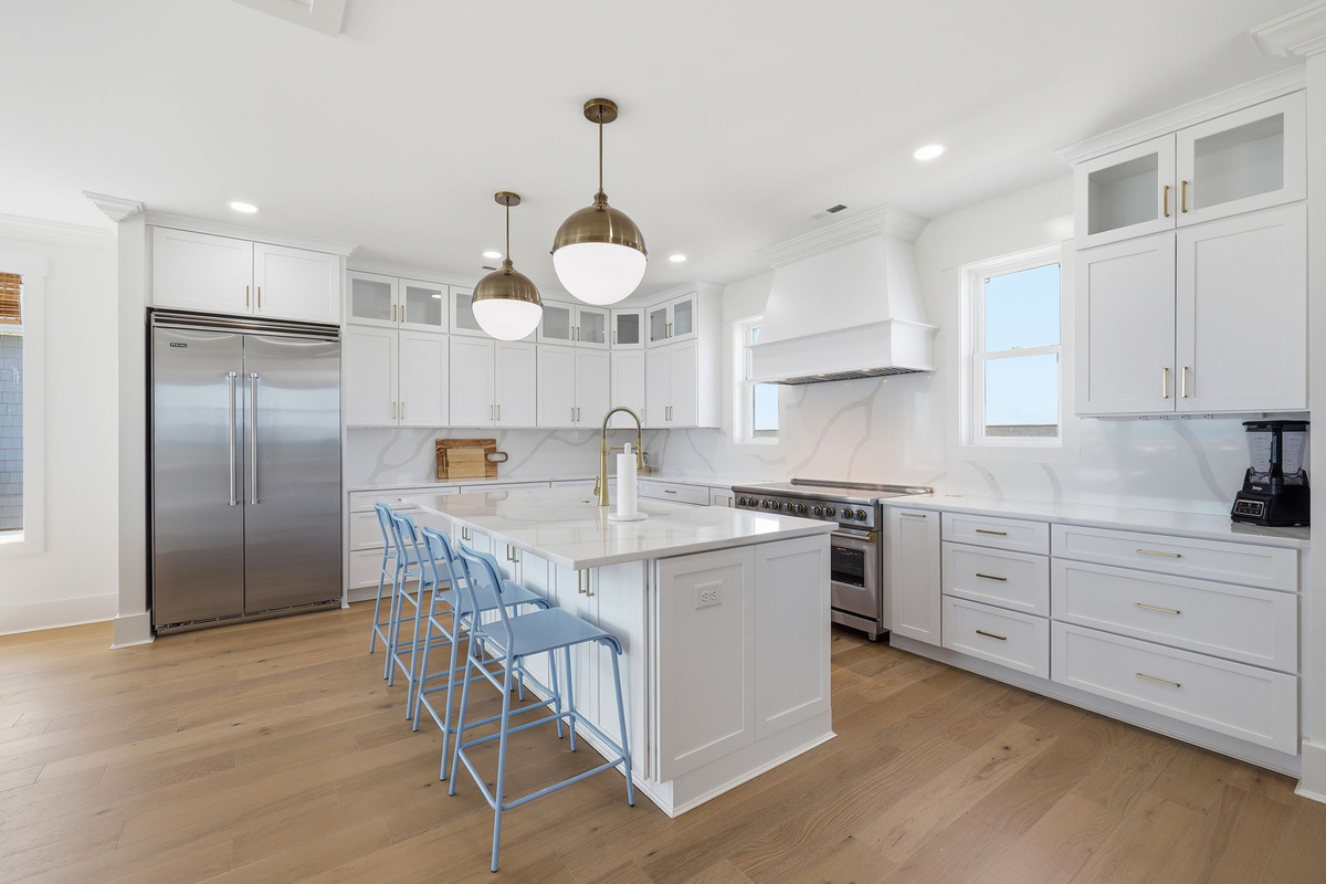 Entertainer&rsquo;s kitchen island with gold fixtures and seamless flow into the oceanview living space