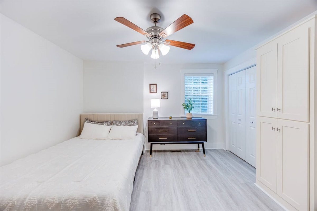 Cozy bedroom featuring a minimalist ceiling fan and a window that lets in fresh air and natural light for a peaceful retreat.